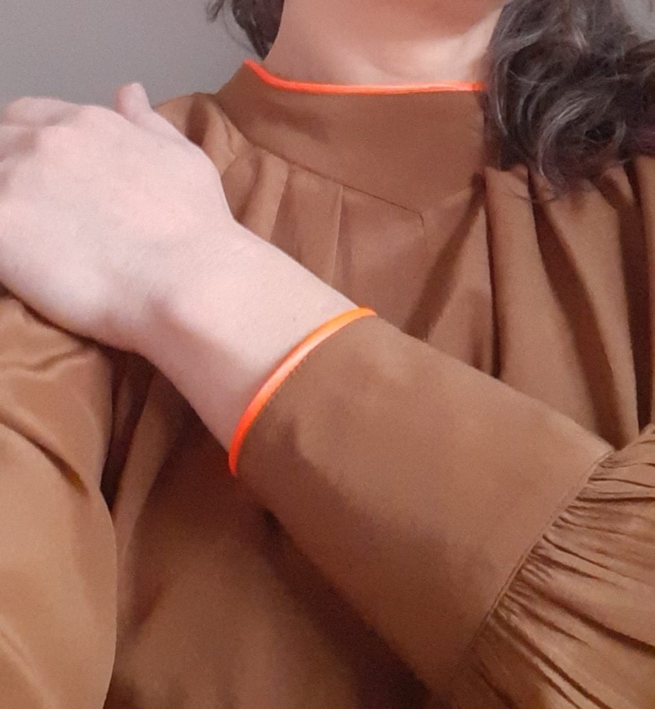 hoge kraag verlaagd en afgewerkt met funky biesje, zelfde afwerking van de manchetten