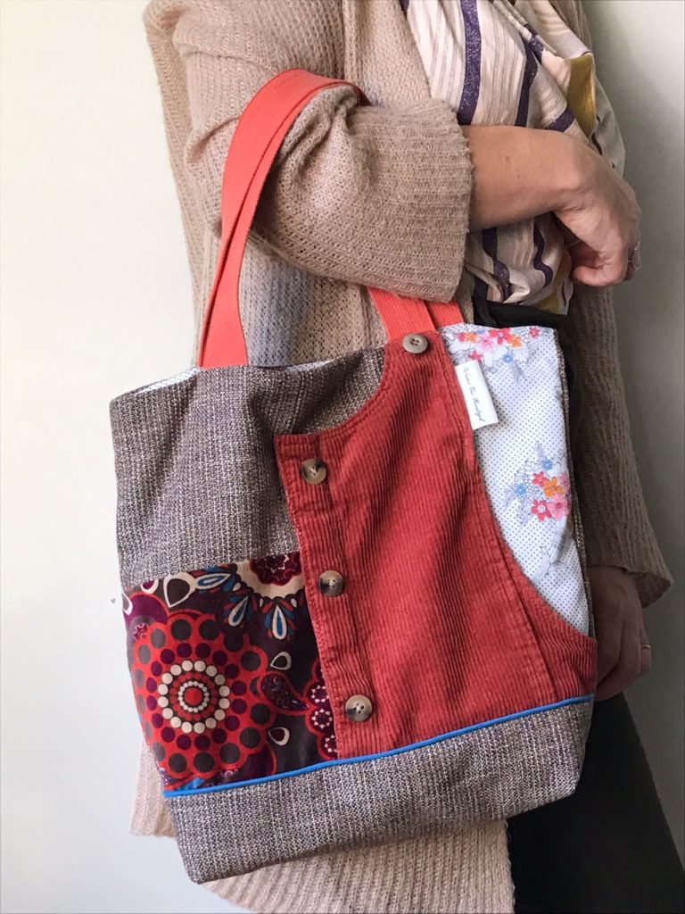 mozaïektas van restjes stof, met bruikbaar zakje op de voorkant met drukknop, binnenzakje met ritssluiting en verstevigde bodem